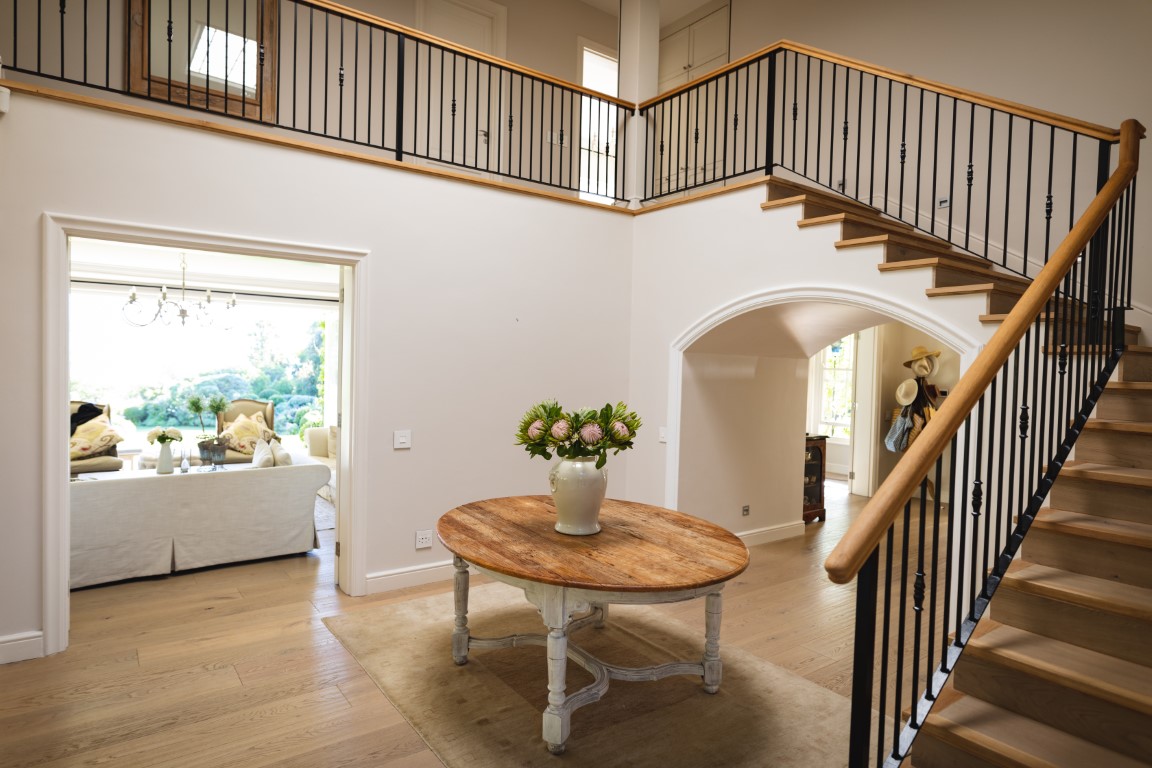 General view of house interior with table and vase with flowers in spacious hallway and staircase. modern interiors and house decoration concept.